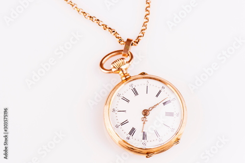 An antique red gold pocket watch against a white background