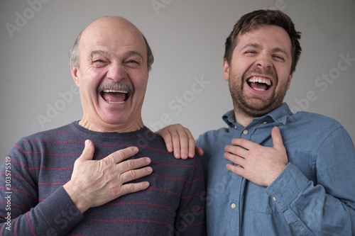 Fototapeta Two men and son laughing on their friend joke having a good mood.