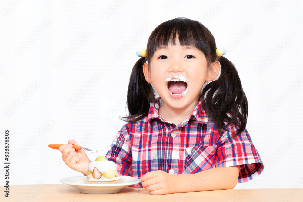 Φωτογραφία 白背景でおやつのケーキを楽しそうに食べる幼い女の子。幸せ、成長、健康イメージ
