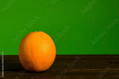 Orange auf braunem Holzuntergrund vor grünem Hintergrund