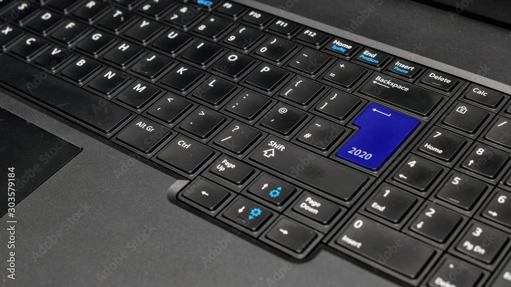 Computer notebook keyboard with blue 2020 key - holiday technology concept