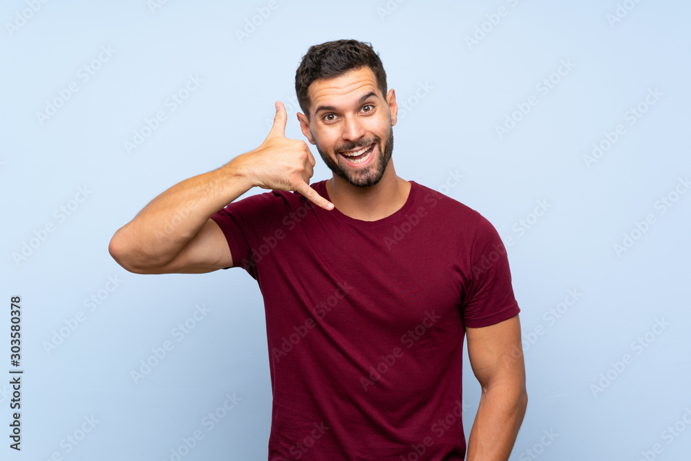 Handsome man over isolated blue background making phone gesture. Call me back sign Handsome man over isolated blue background making phone gesture. Call me back sign