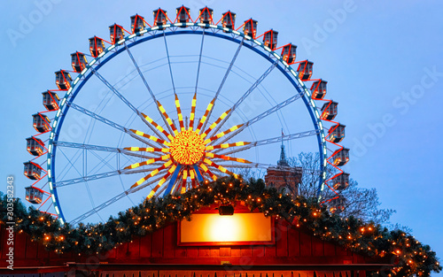 Ferris Wheel of Night Christmas Market at Town Hall Winter Berlin, Germany. German street Xmas and holiday fair in European city or town. Advent Decoration and Stalls with Crafts Items on Bazaar