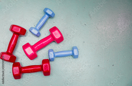 Dumbbells of blue and red lie on a gray background. View from above