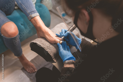 Fotografie Pedicure master uses nail file drill  for preparing nails for pedicure