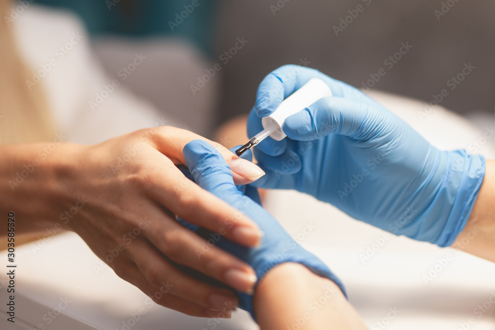 Manicurist varnishes the client's nails, making french style.  Manicure process close up