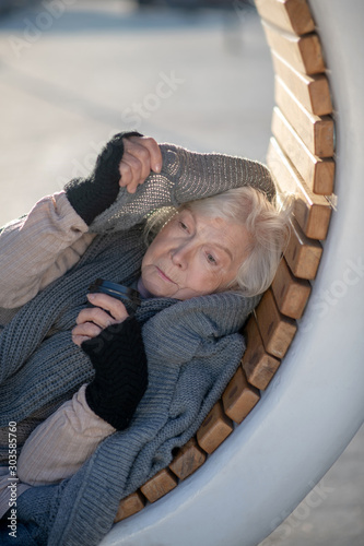 Homeless pensioner wearing grey sweater while feeling cold photo