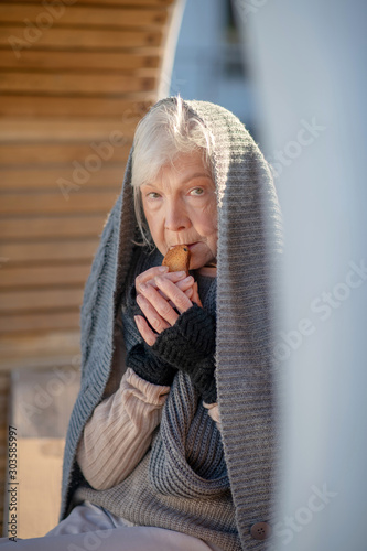 Homeless pensioner wearing scarf holding little cracker photo