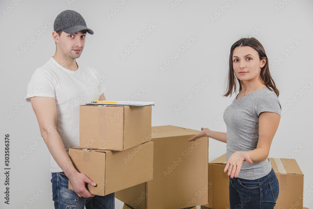 Young woman moving into new place, but she doesn't understand why delivery guy brought her two cardboard boxes, which don't belong her. Young woman moving into new place, but she doesn't understand why delivery guy brought her two cardboard boxes, which don't belong her.