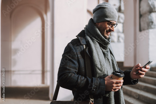 Adult Caucasian guy using his new mobile phone outside