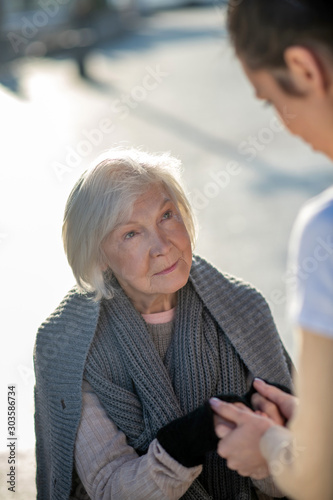 Aged homeless woman feeling happy while talking to volunteer photo