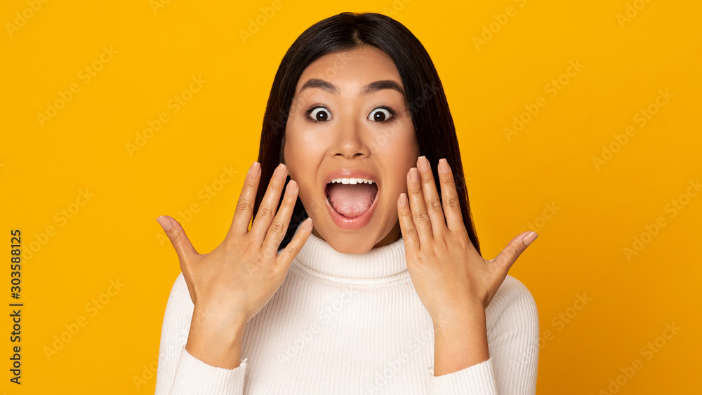 Wow. Surprised asian girl shouting over yellow background - obrazy, fototapety, plakaty 