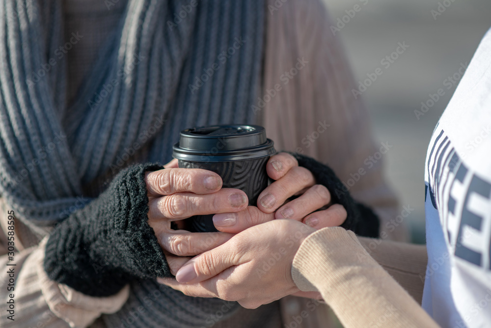 Φωτογραφία Close up of kind volunteer giving cup of hot tea to poor woman