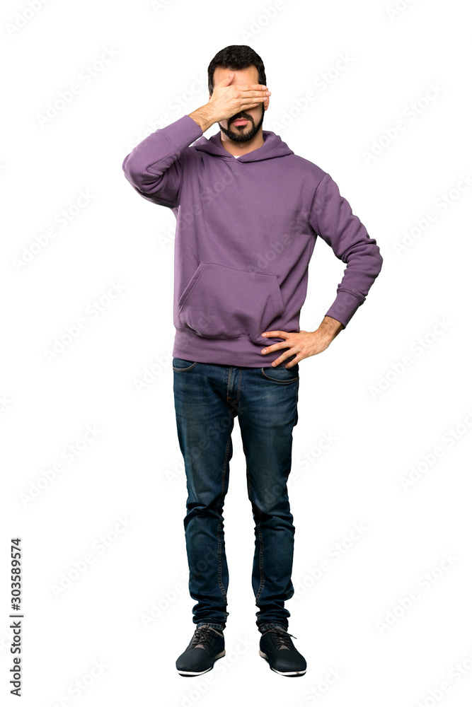 Full-length shot of Handsome man with sweatshirt covering eyes by hands. Do not want to see something over isolated white background