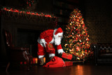 Christmas night, Santa Claus puts gifts under the tree 