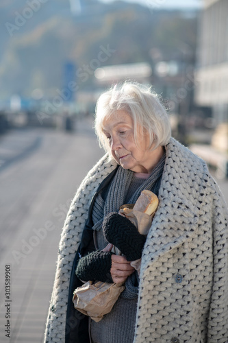 Grey-haired homeless pensioner having only bread to eat photo