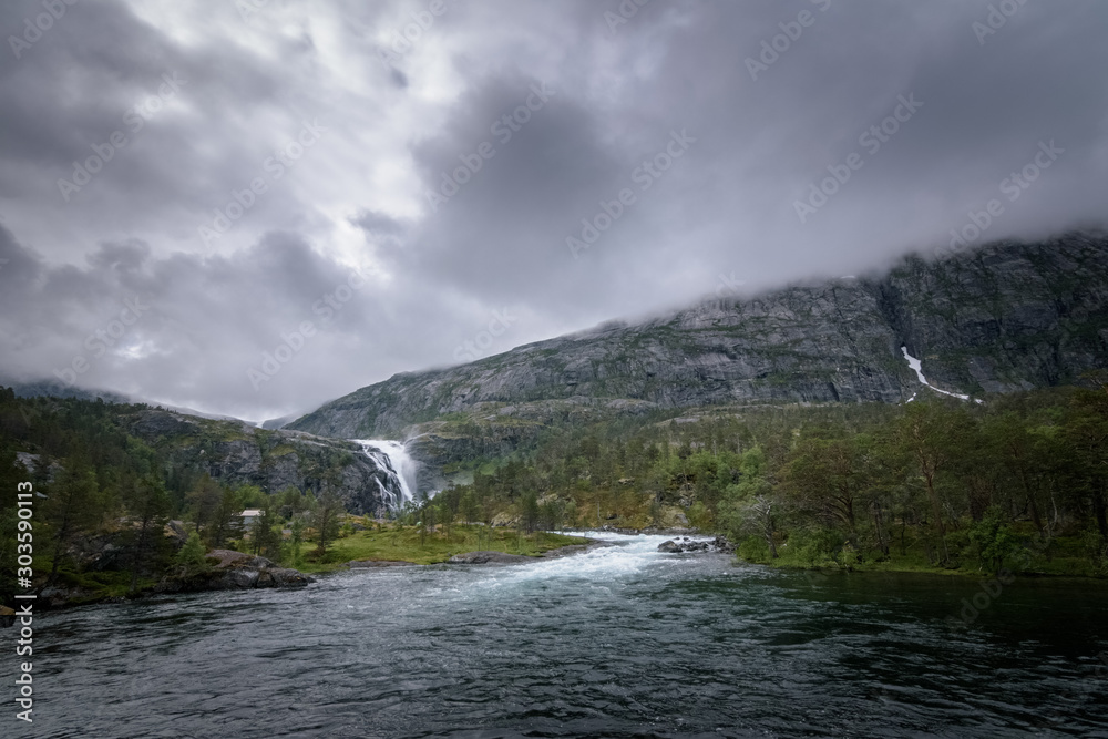 Distant view on nykkjesoyfossen waterfall in dark rainy weather Norway