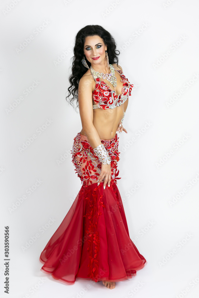 Brunette in a beautiful long dress to perform belly dance on a white background