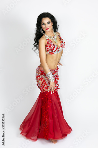 Brunette in a beautiful long dress to perform belly dance on a white background