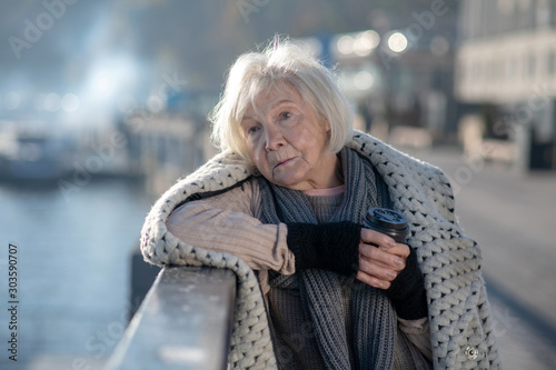Poor homeless woman feeling thoughtful while staying alone photo