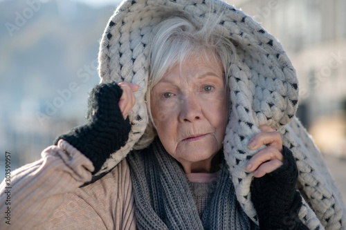 Blue-eyed homeless pensioner feeling very cold and unprotected photo