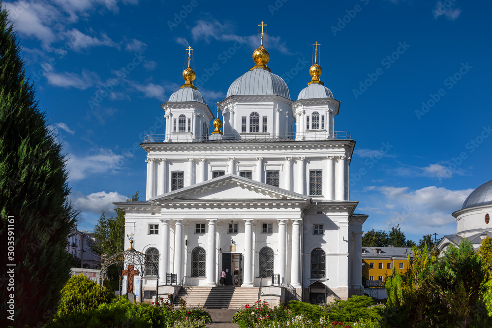 Russia, Golden Ring, Yaroslavl, near Volga river: Front view of famous orthodox onion domed Kasan Convent in the city center of the Russian town with green garden, women and blue sky.