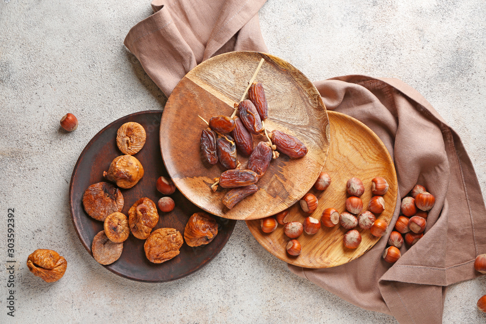 Plates with different dried fruits ad nuts on grey background Plates with different dried fruits ad nuts on grey background