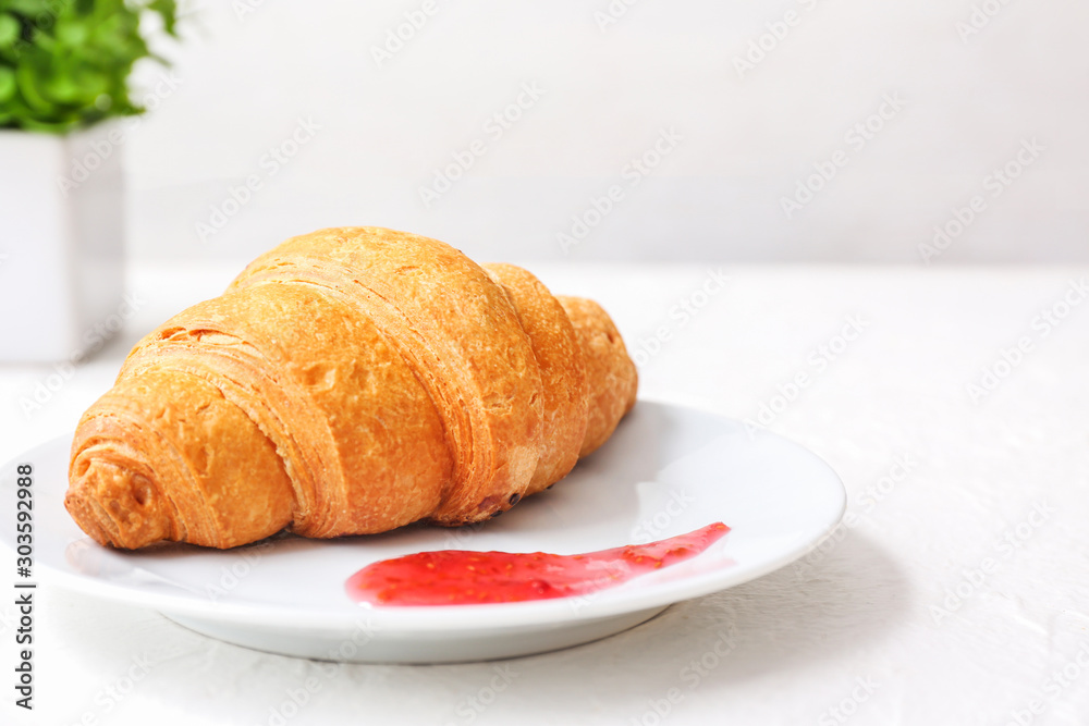 Plate with tasty sweet croissant and jam on table
