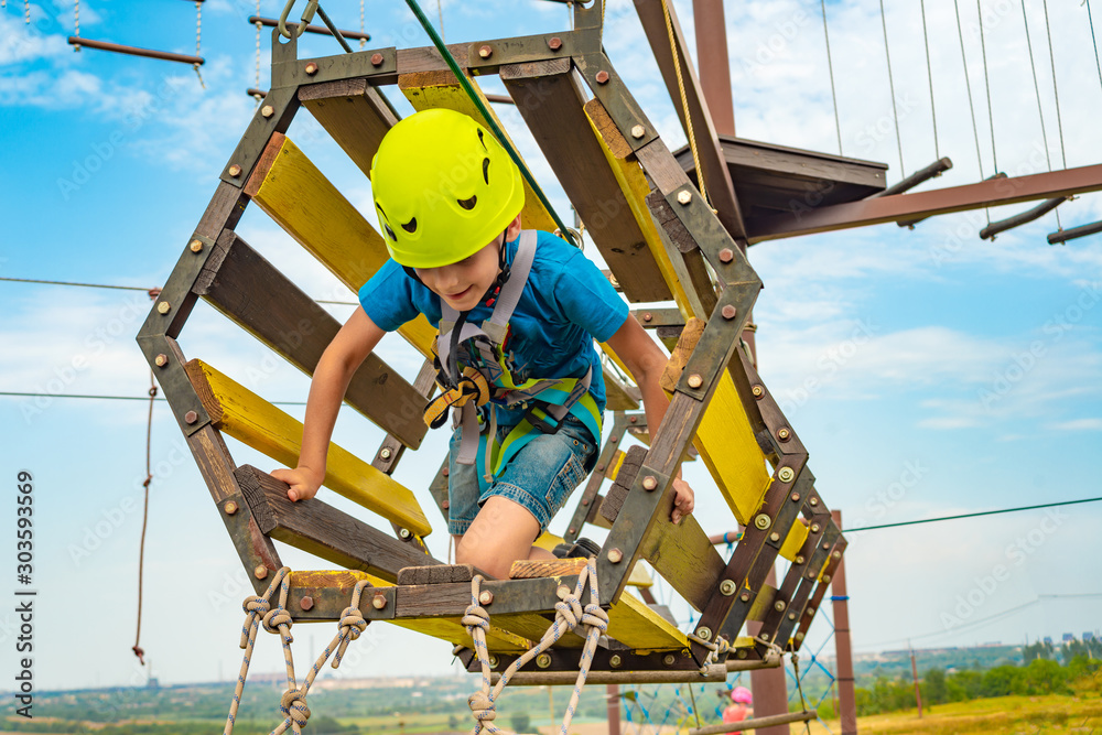 A boy on an obstacle course overcomes difficulties with moving in a sports amusement park. A boy on an obstacle course overcomes difficulties with moving in a sports amusement park.