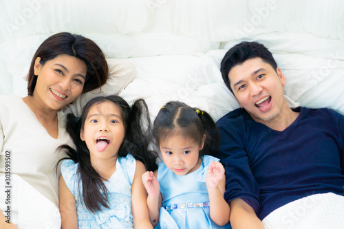 Asian happy family play together on bed