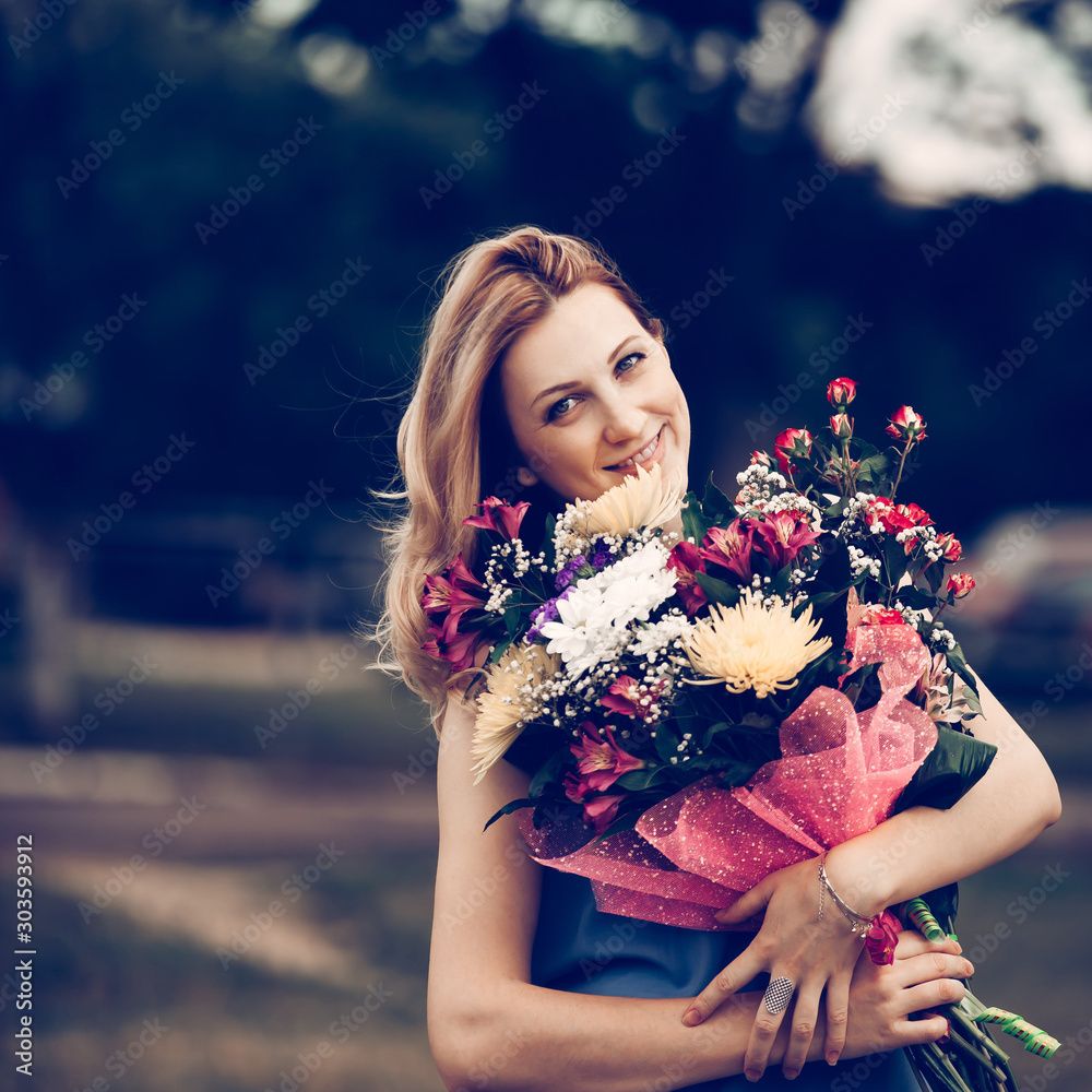 beautiful woman with a bouquet of flowers on a blurred background of the Park