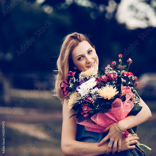Obraz na płótnie beautiful woman with a bouquet of flowers on a blurred background of the Park w salonie