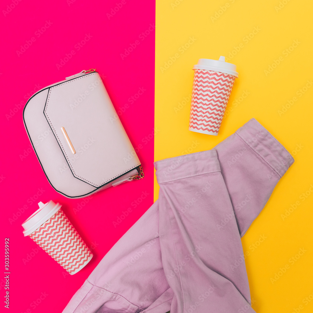 Φωτογραφία Fashionable laid out set: handbag, coffee cups and two sleeves of pink denim jacket on fuchsia and bright yellow colored background
