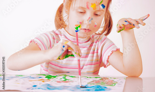 Funny humorous photo of little cute child girl painting with a brushes. Art  creativity and childhood concept.