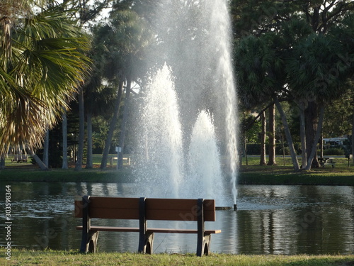 water fountain jets in pond with park bench