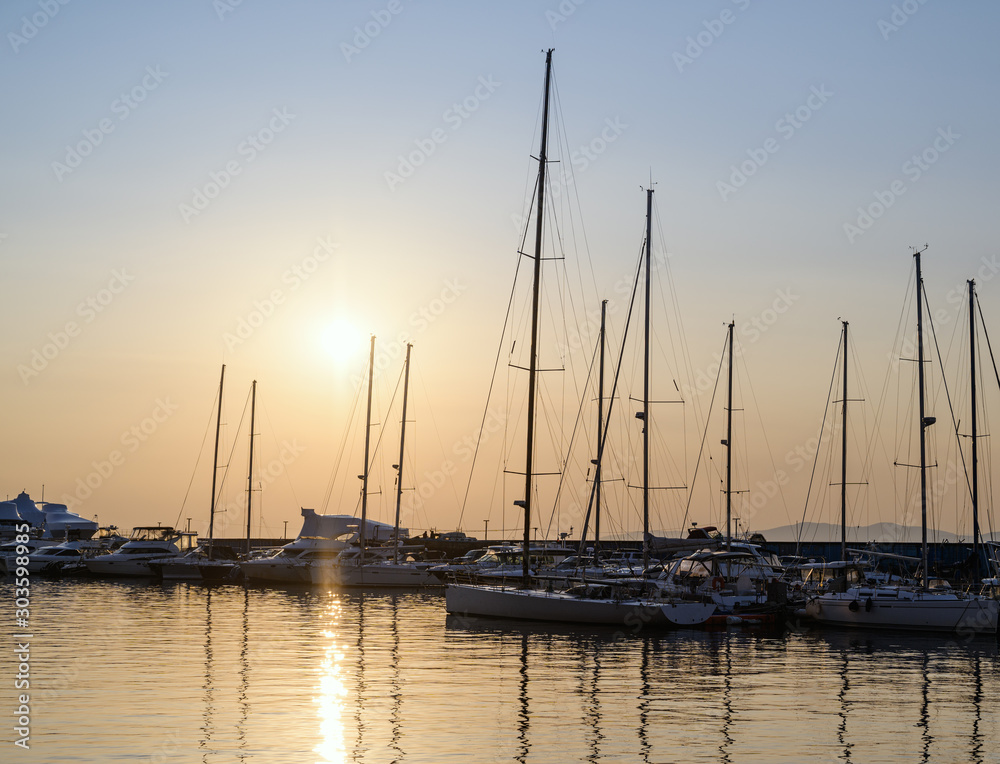 Yachts and boats reflected in water at the sunset - marina view.
