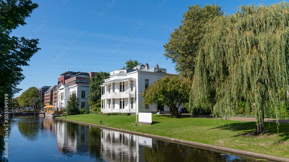  the Hague canal with houses, green trees on a sunny day, netherlands