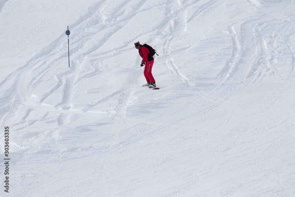 Snowboarder in red downhill on snowy off-piste slope
