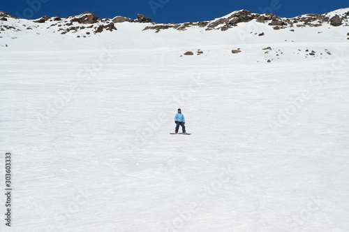 Snowboarder on off-piste ski slope in high snowy mountains