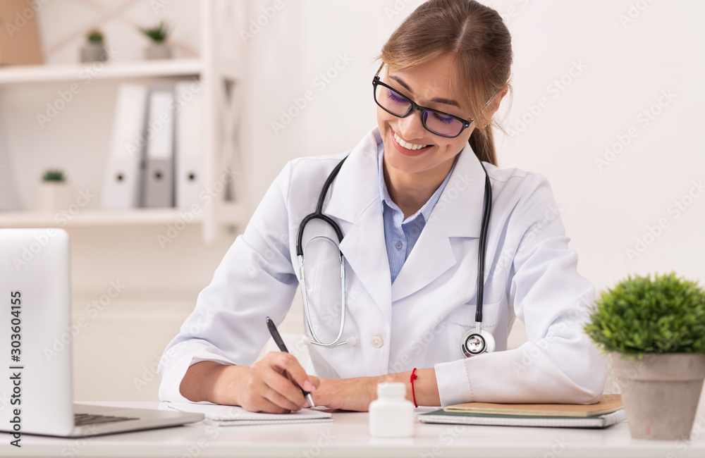 Smiling Doctor Lady Prescribing Medication Treatment Sitting At Workplace Smiling Doctor Lady Prescribing Medication Treatment Sitting At Workplace