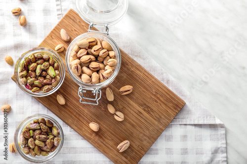 Bowls and jar with tasty pistachio nuts on table