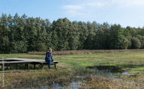 mature woman is resting in nature on a wooden platform in the Veluwe © Chris Willemsen 