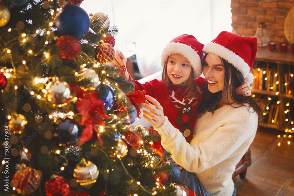 Smiling mom and daughter decorating Christmas tree - obrazy, fototapety, plakaty 