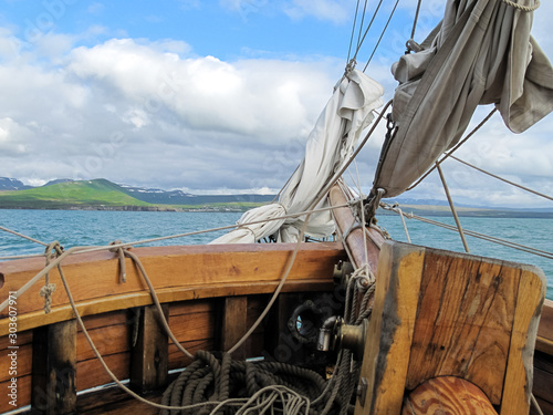 View from the bow of an old sailboat sailing in the Arctic sea with land in the background photo
