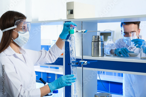 Scientist pouring liquid through glass distillation condenser indoors. Laboratory analysis photo