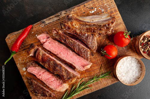 Beef steak, herbs and spices on a cutting board on a background of stone