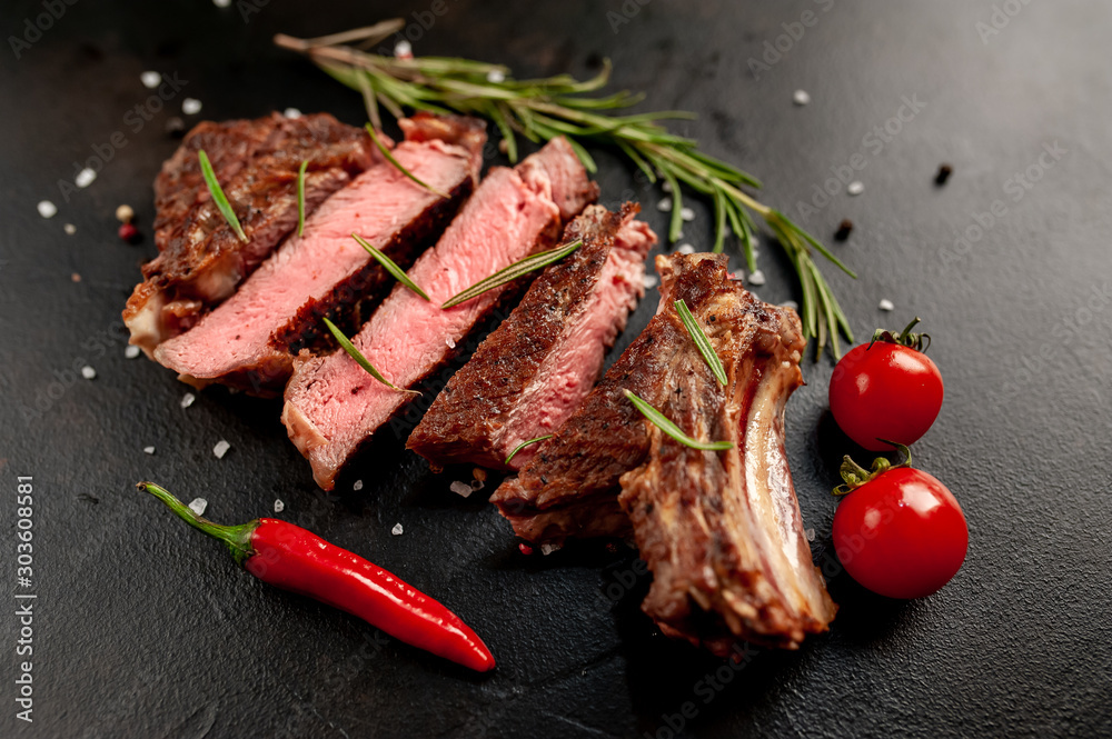 Beef steak, herbs and spices on a stone background, top view