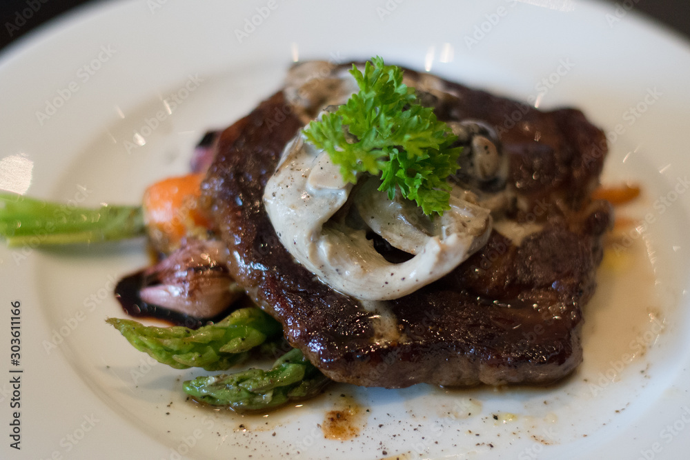 Grilled sirloin beef steak on bed of grilled asparagus and mushroom cream sauce