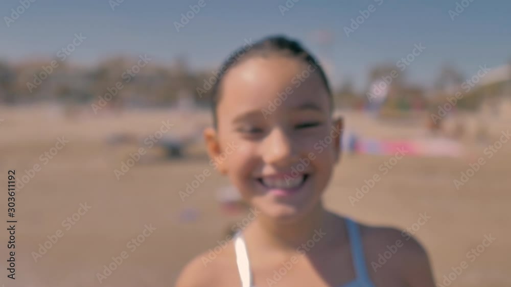 niña sonriente con bañador plateado en la playa