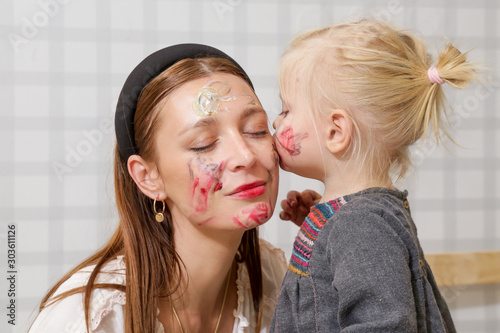 Mom and baby playing with face paint, family time concept